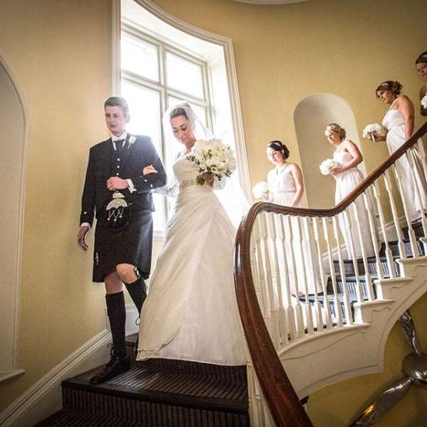 Bride and bridesmaids walking down a stairwell at Kesgrave Hall